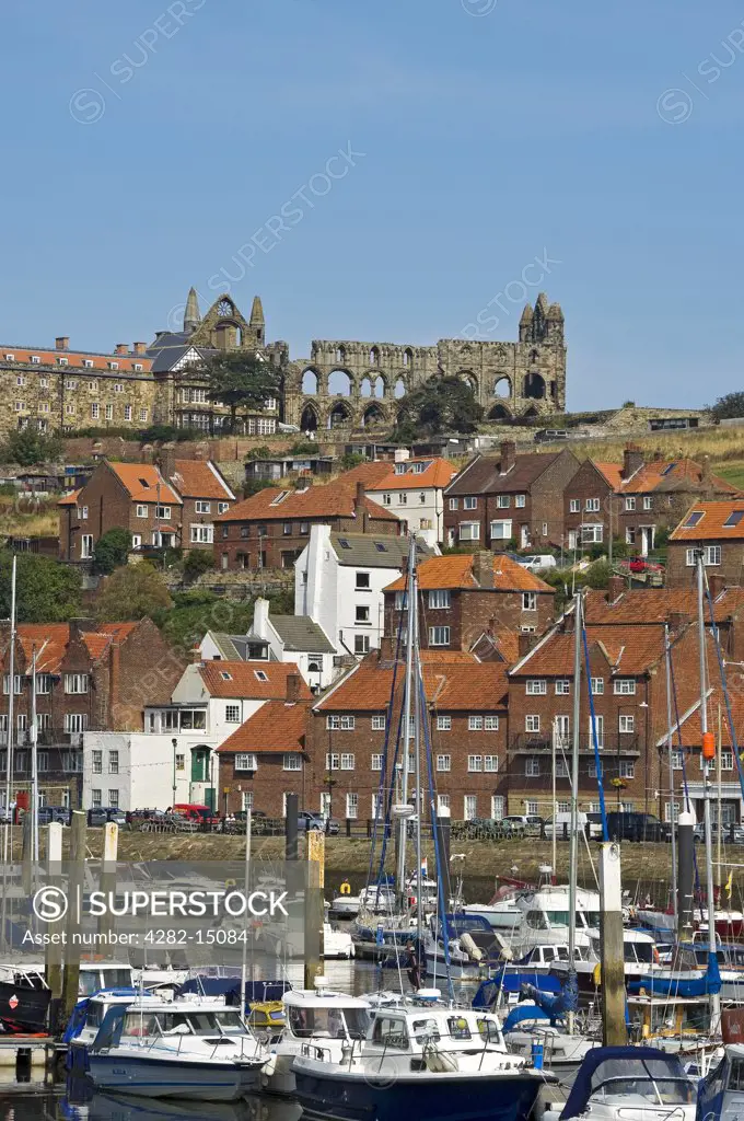 England, North Yorkshire, Whitby. Boats moored on the River Esk with Whitby Abbey in the background.