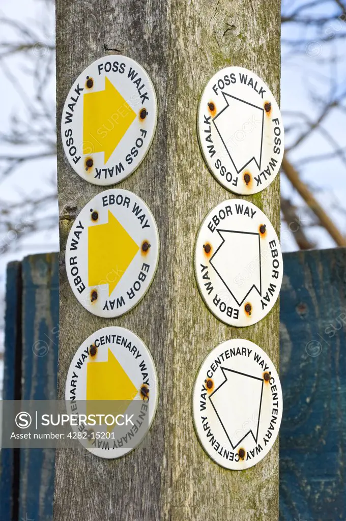 England, North Yorkshire, near York. Signs on a wooden post with arrows showing directions for Centenary Way, Ebor Way and Foss Walk near York.