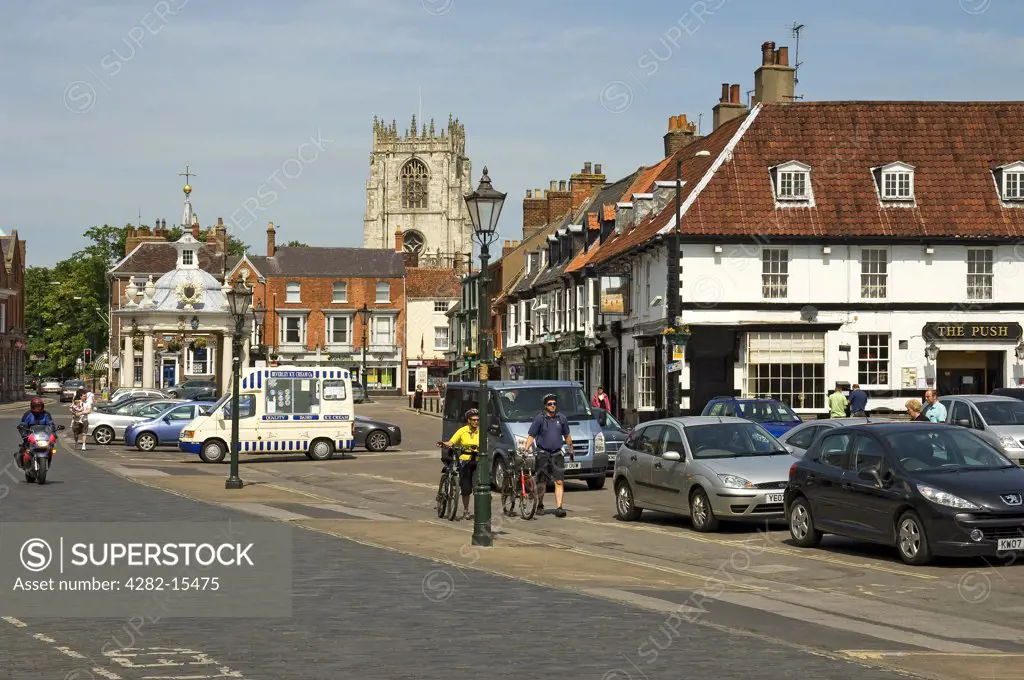England, East Riding of Yorkshire, Beverley. Two cyclists walk their bicycles past Market Cross in Saturday Market, Beverley.