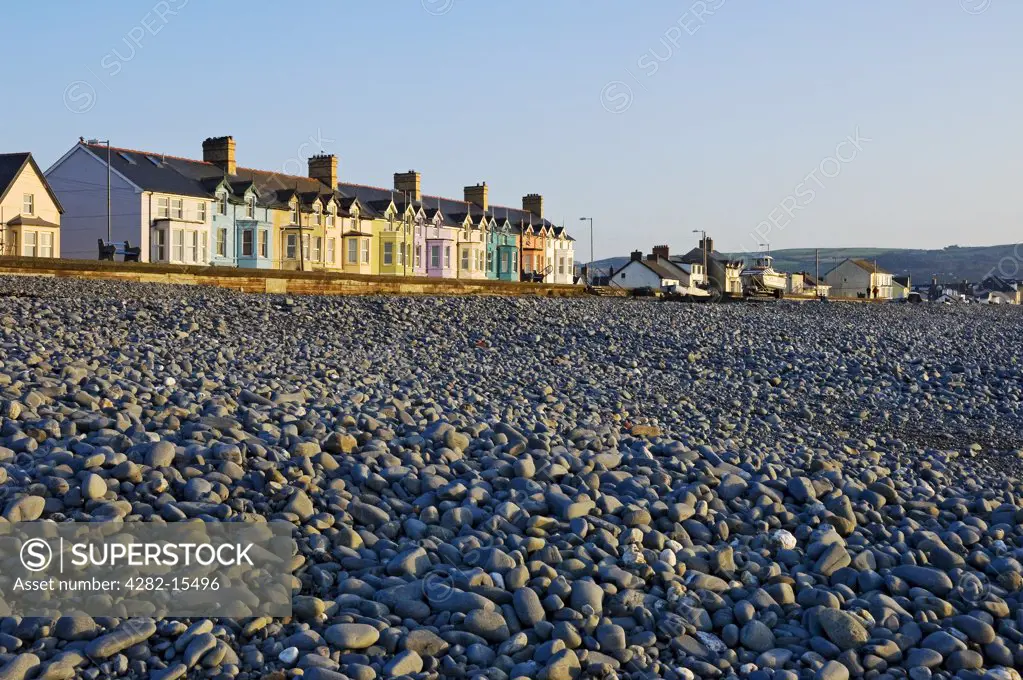 Wales, Ceredigion, Borth. View over a pebble beach towards colourful houses along the seafront at Borth.