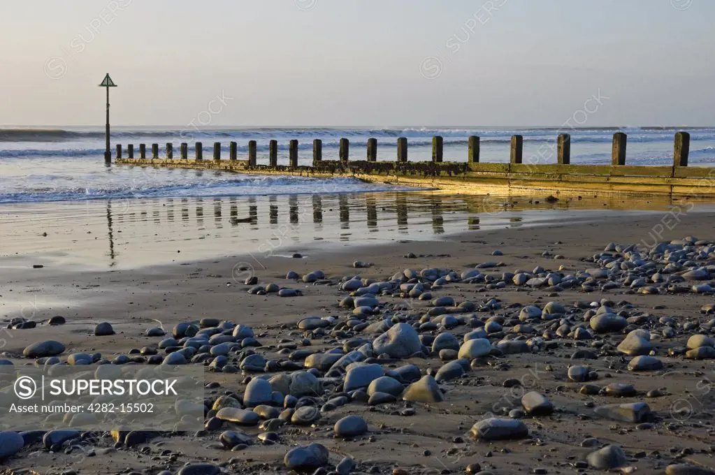 Wales, Ceredigion, Borth. Waves rolling onto the beach past a breakwater.