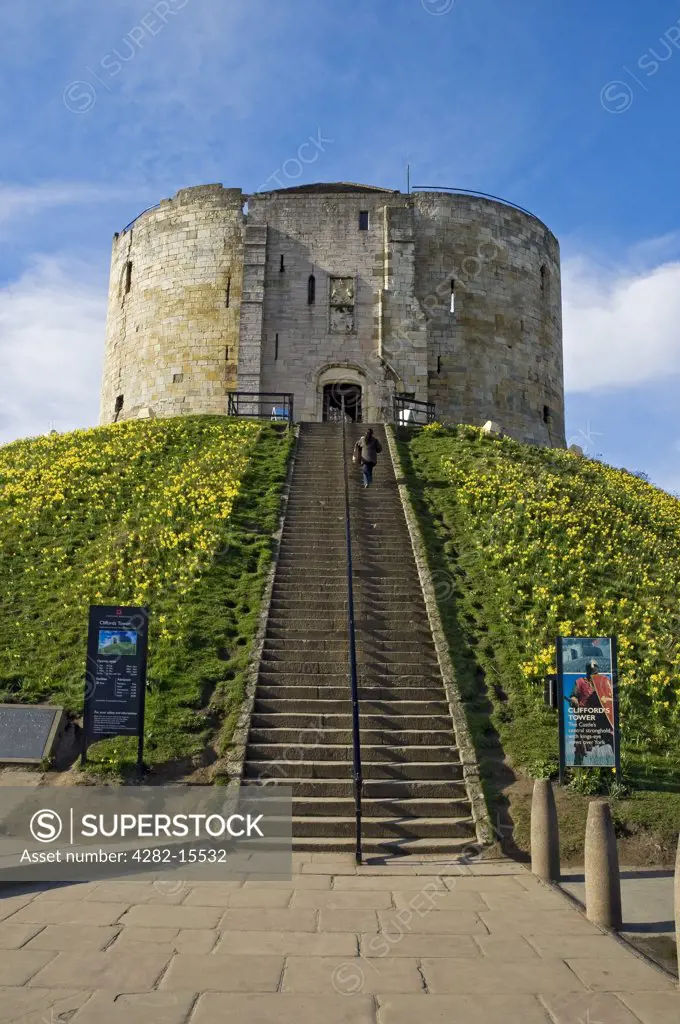 England, North Yorkshire, York. A woman walking up steps to Clifford's Tower, all that remains of York Castle originally built by William the Conqueror.