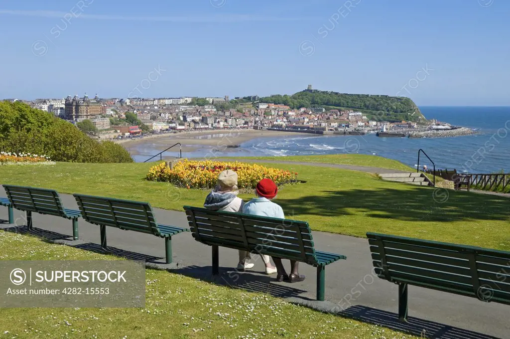 England, North Yorkshire, Scarborough. Two elderly women sitting on a bench looking out to sea over South Bay beach.