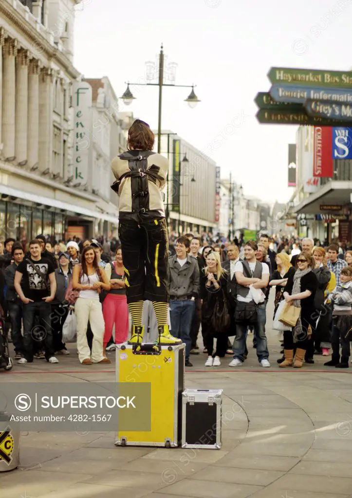 England, Tyne and Wear, Newcastle Upon Tyne. An escapologist standing on a box performing to a crowd on Northumberland Street.