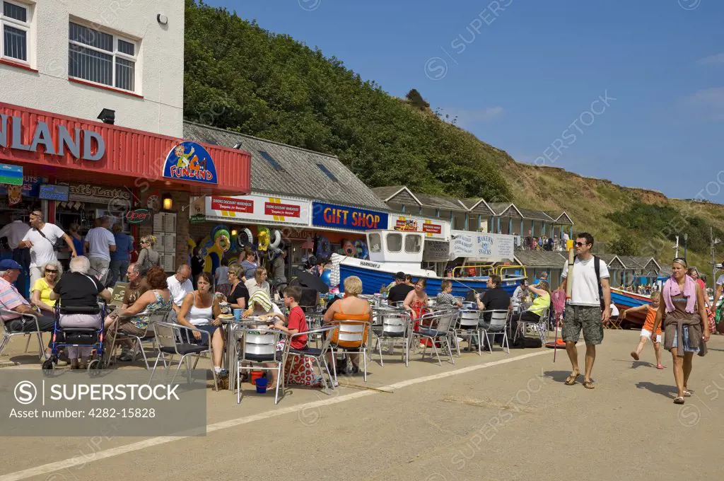 England, North Yorkshire, Filey. Holidaymakers eating outside a cafe on the Coble Landing.