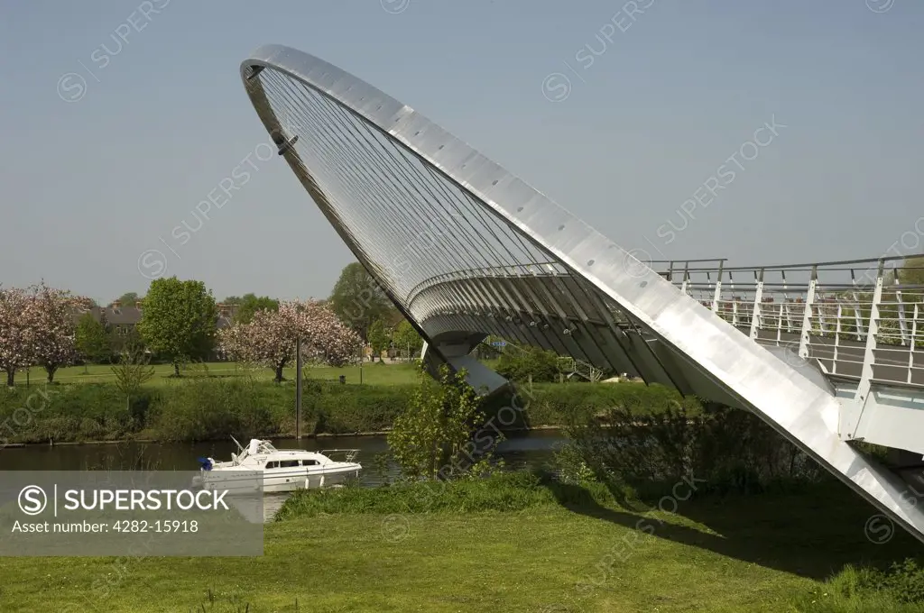 England, North Yorkshire, York. A small leisure boat passing under the Millennium Bridge on the River Ouse in York.