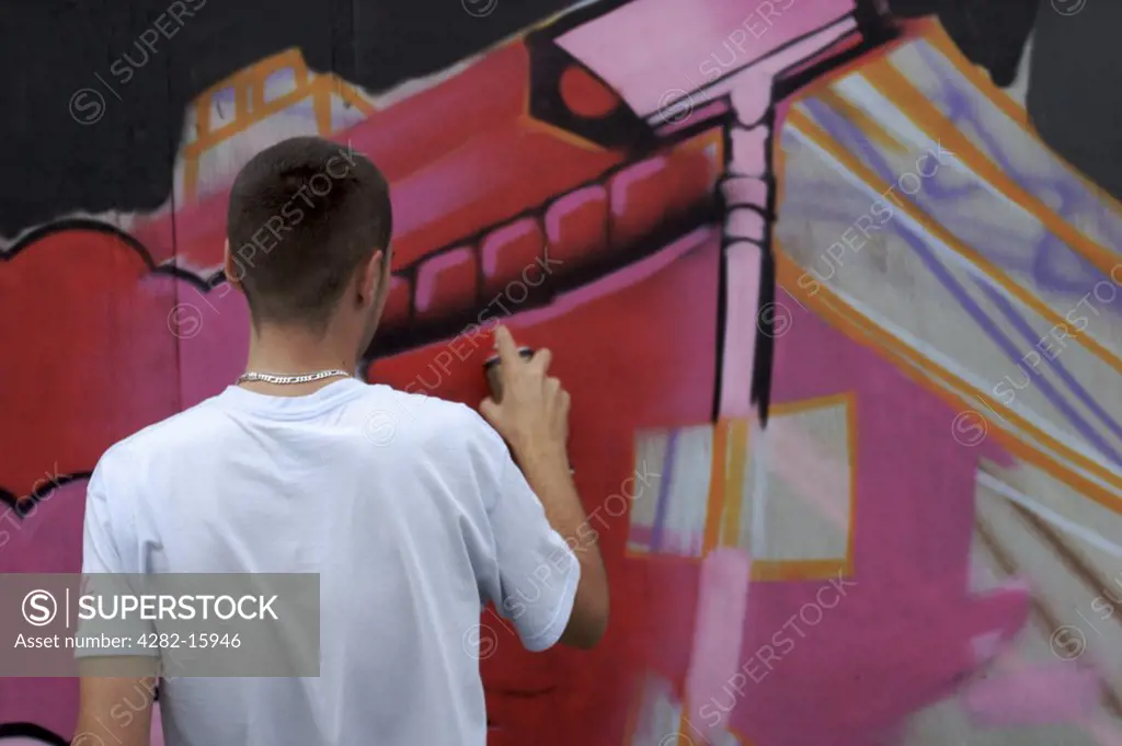 England, East Sussex, Brighton. Graffiti artist paints cctv camera. The word 'graffiti' is the plural of 'graffito' and originates from the Italian word 'graffiato' which means scratched.