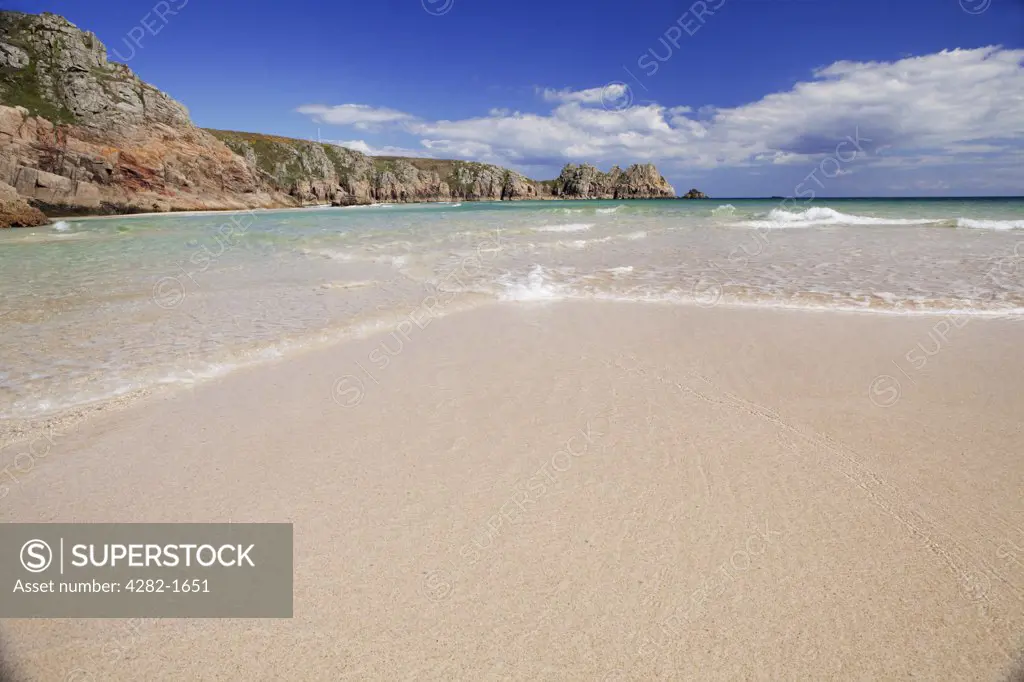 England, Cornwall, Porthcurno. Low tide on the sandy beach at Porthcurno with Logan rock in the distance.