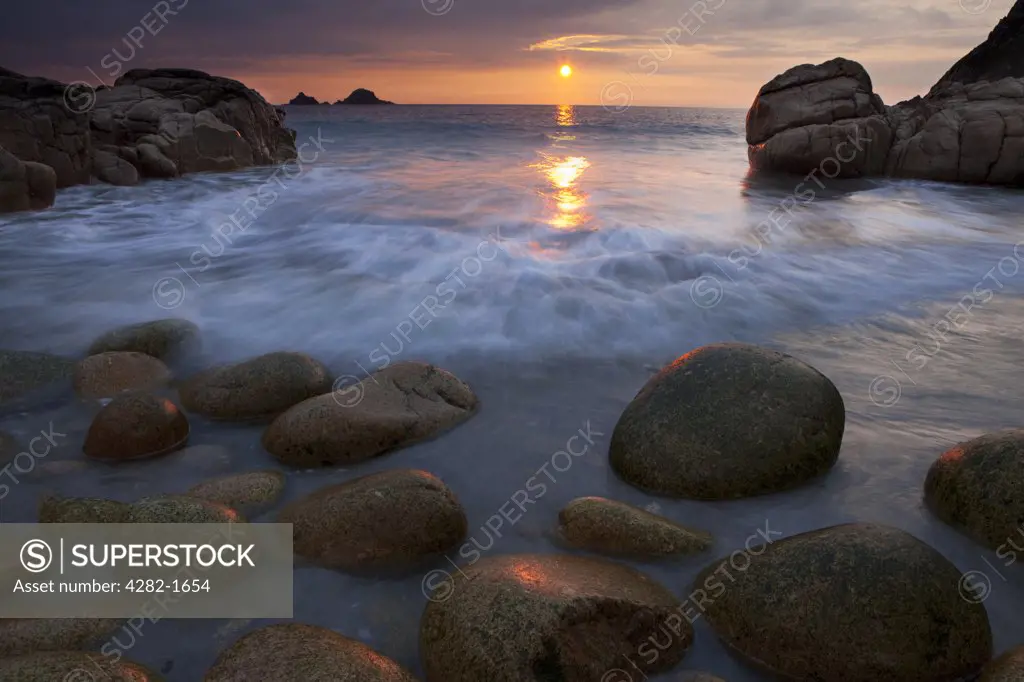 England, Cornwall, Porth Nanven. Sunset over the sea viewed from Porth Nanven, a beach sometimes referred to as 'Dinosaur Egg Beach' because of large deposit of ovoid boulders on the beach and foreshore.