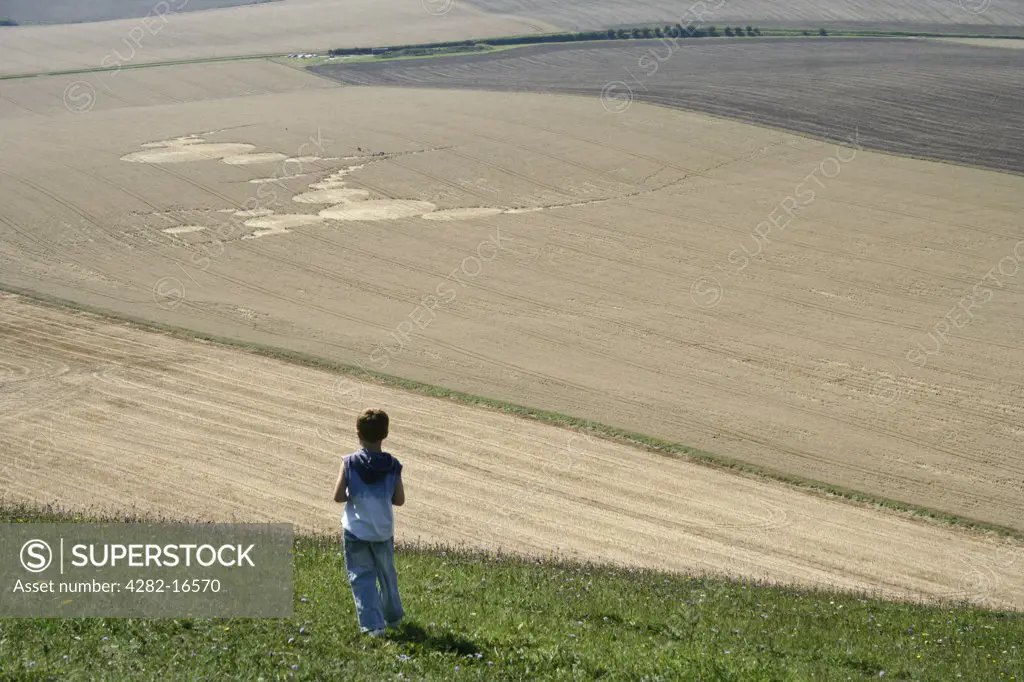 England, Wiltshire, Knapp Hill. A small boy looks at a crop circle formed in a field at Knapp Hill.