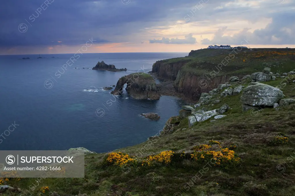 England, Cornwall, Land's End. A view of Land's End (the most westerly point in England) at sunset with Longships Lighthouse in the distance.