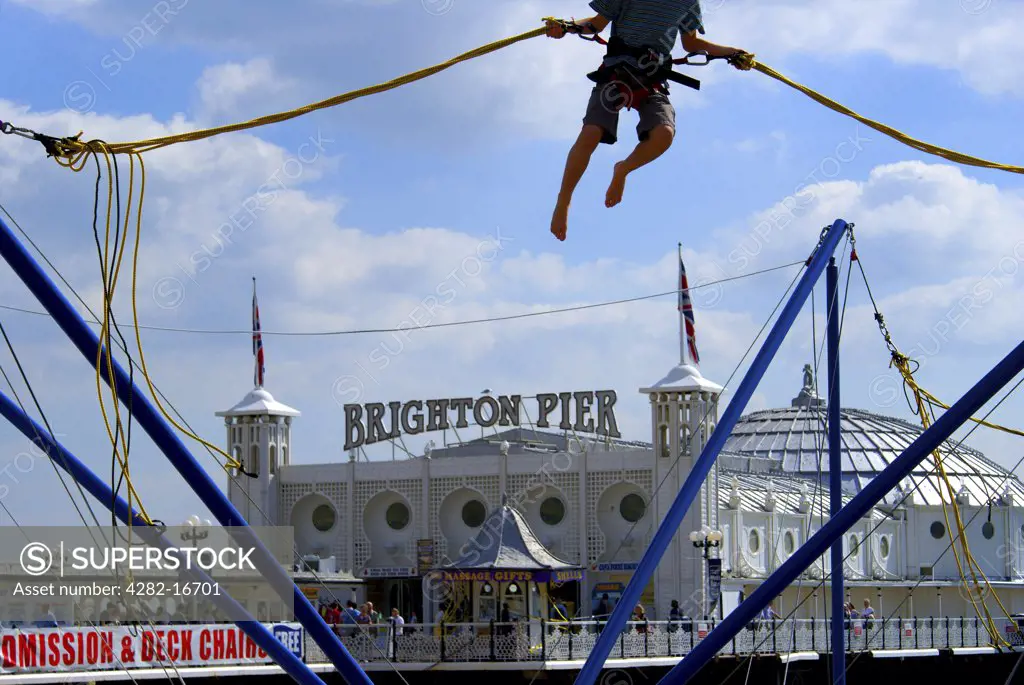 England, City of Brighton and Hove, Brighton. Boy on a Bungee in front of Brighton Pier.