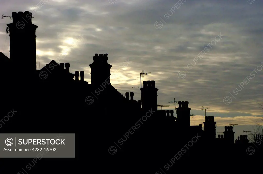 England, City of Brighton and Hove, Hove. Row of chimney pots in silhouette against a grey sky in Hove.