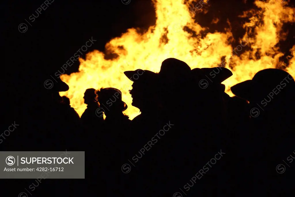 England, East Sussex, Hastings. People in Traditional costume silhouetted against bonfire flames.