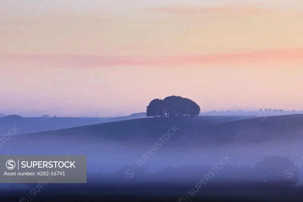 England, Wiltshire, Avebury. Morning mist over the rolling hills near Avebury.