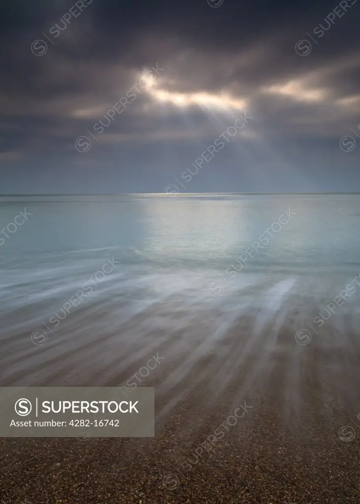 England, Dorset, Burton Bradstock. Crepuscular rays over the sea at Burton Bradstock.