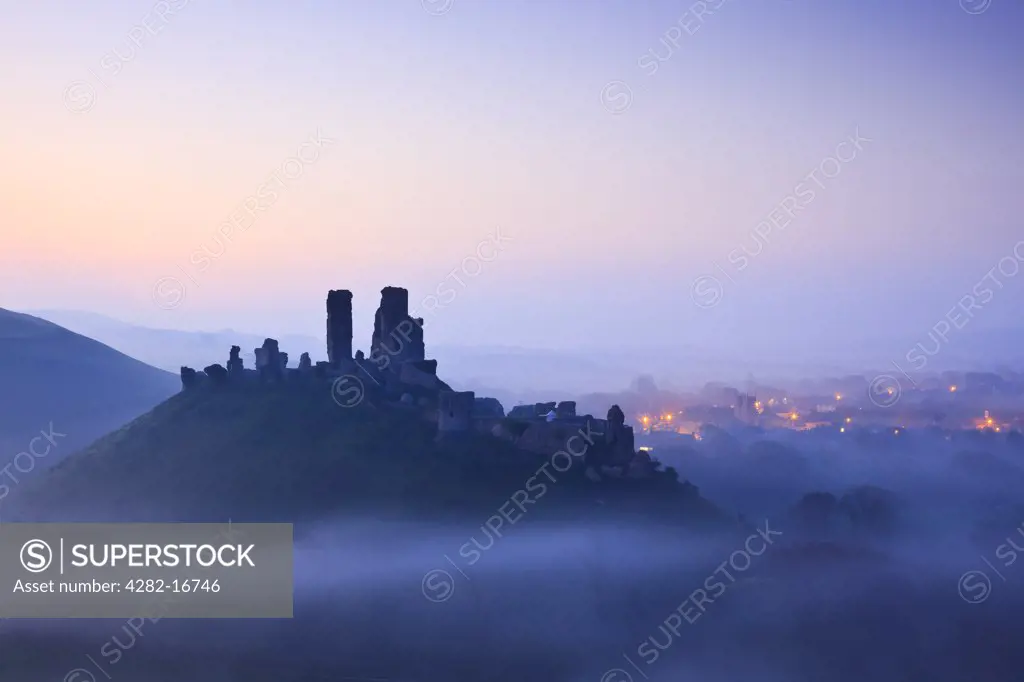 England, Dorset, Corfe Castle. Corfe Castle, dating back to the 11th century, rising above pre-dawn mist.