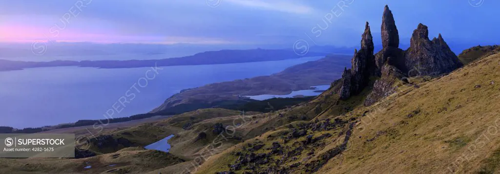 Scotland, Isle of Skye, Trotternish. Panoramic view of the Old Man of Storr, dramatic pinnacles of rock remaining from ancient landslips on the Trotternish peninsula with the Cuillin ridge in the background.