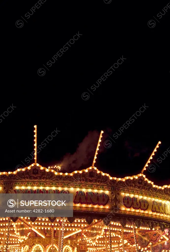 England, Lincolnshire, Grantham. Carousel at night. The word carousel originates from the Italian garosello meaning 'little war', used by crusaders to describe a combat preparation exercise game played by Turkish and Arabian horsemen in the 1100's.