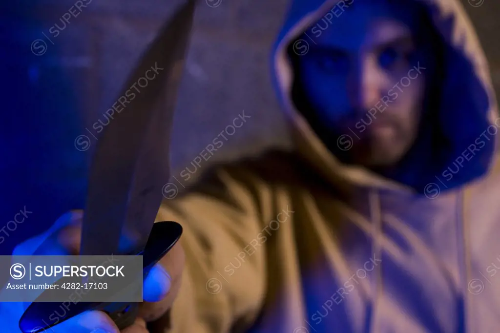 England, County Durham, Durham. Hooded gang member holding out a knife.