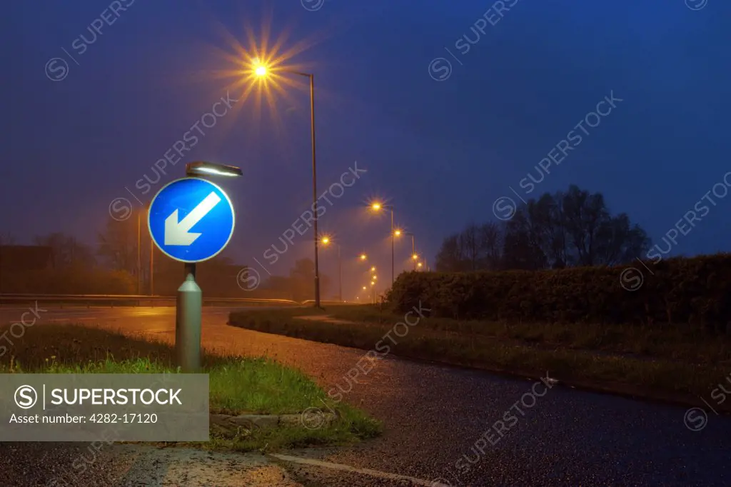 England, County Durham, Durham. A road sign indicating to keep left, lit up at dusk.