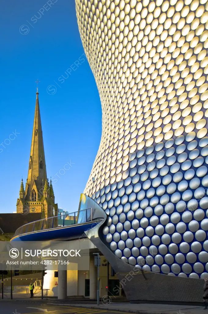 England, West Midlands, Birmingham. The aluminium disc clad exterior of Selfridges iconic store at the Bullring and St Martin's Church at sunrise.
