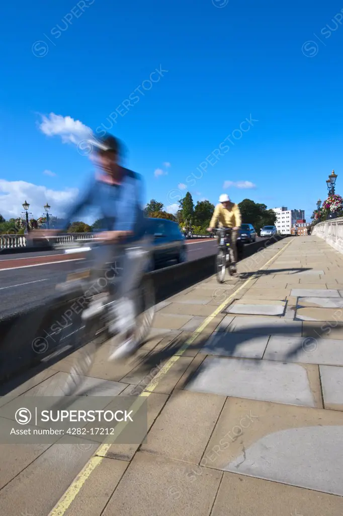 England, Surrey, KIngston upon Thames. Cyclists riding in a cycle lane over Kingston Bridge.