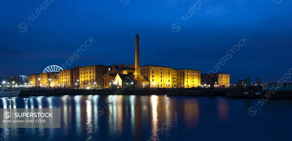 England, Merseyside, Liverpool. Albert Dock buildings at night with reflections in the waters of Canning Dock. The Albert Dock complex was the world's first buidling built using only cast iron, brick and stone, without the use of structural wood. It has the largest concentration of Grade 1 listed buildings in the UK.