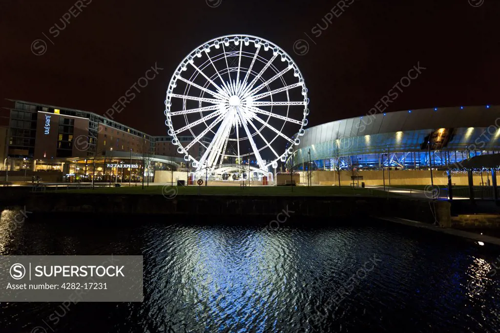 England, Merseyside, Liverpool. Night view of Echo Arena and Echo Liverpool Wheel reflected in the waters of Dukes Dock.
