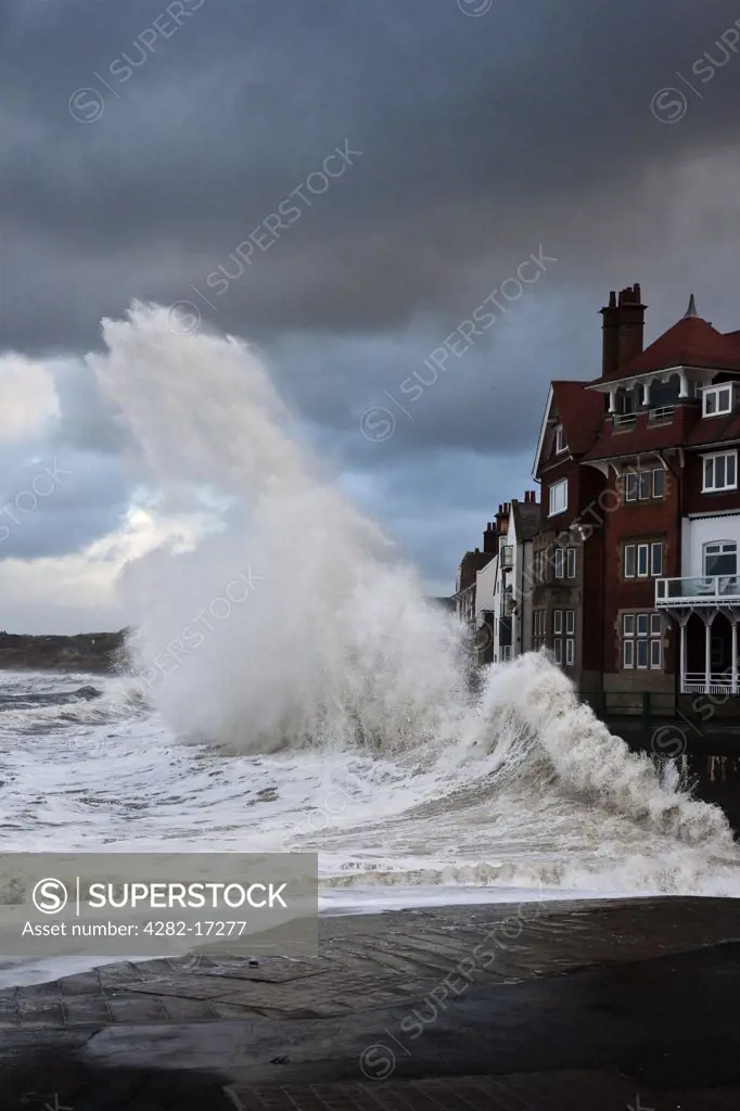 England, North Yorkshire, Sandsend. Rough North sea conditions create a spectacular sight as waves break against the seafront at Sandsend.