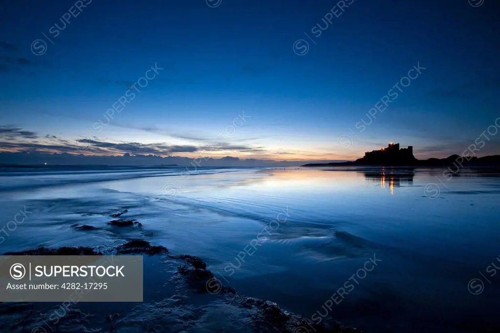 England, Northumberland, Bamburgh. Bamburgh Castle, former home to the Kings of Northumbria, located on a large whinstone outcrop, silhouetted in the pre-dawn light.
