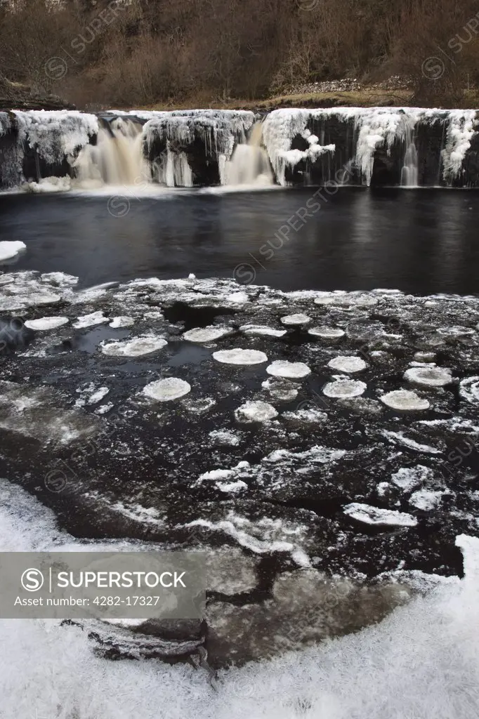 England, North Yorkshire, Upper Swaledale. Wain Wath Force on the River Swale, frozen in winter, in the Yorkshire Dales National Park.