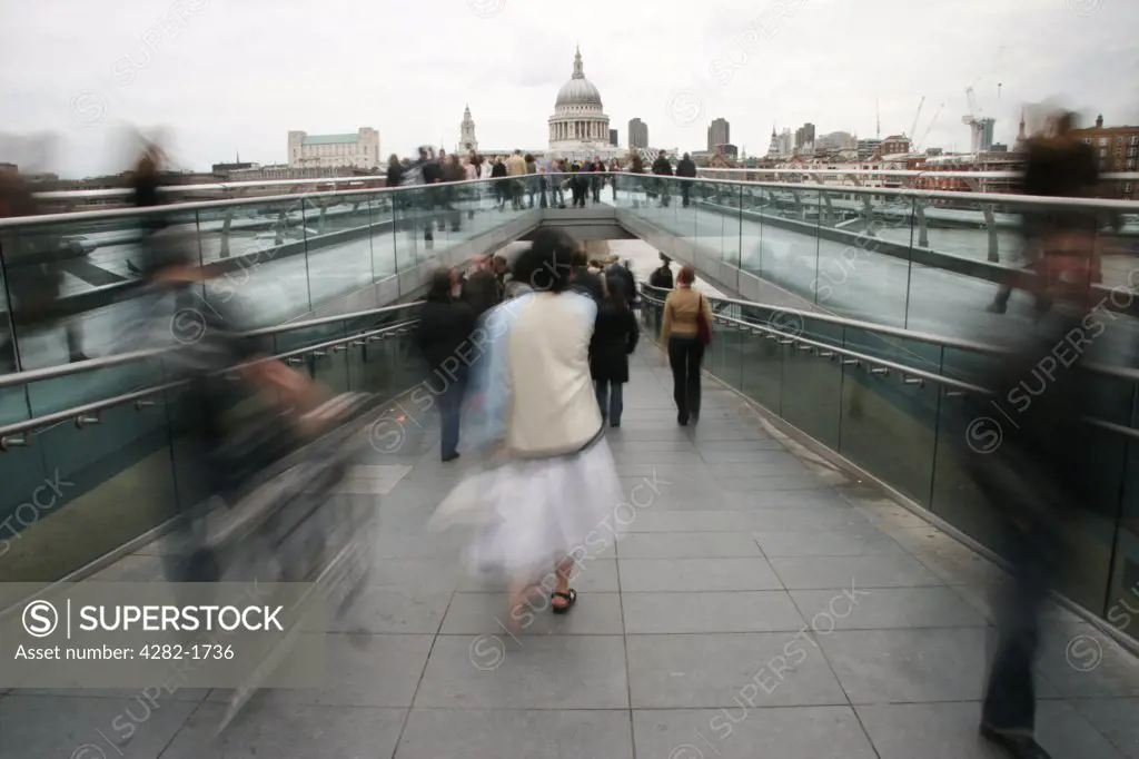 England, London, South Bank. People moving across the Millennium Bridge towards St. Paul's Cathedral in London.