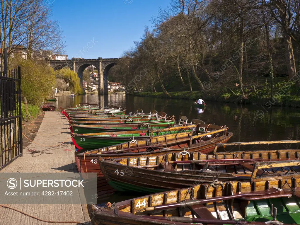 England, North Yorkshire, Knaresborough. Rowing boats for hire on the River Nidd. The Knaresborough Viaduct, built in 1851 to carry Victorian rail traffic over the Nidd Gorge, is in the background.
