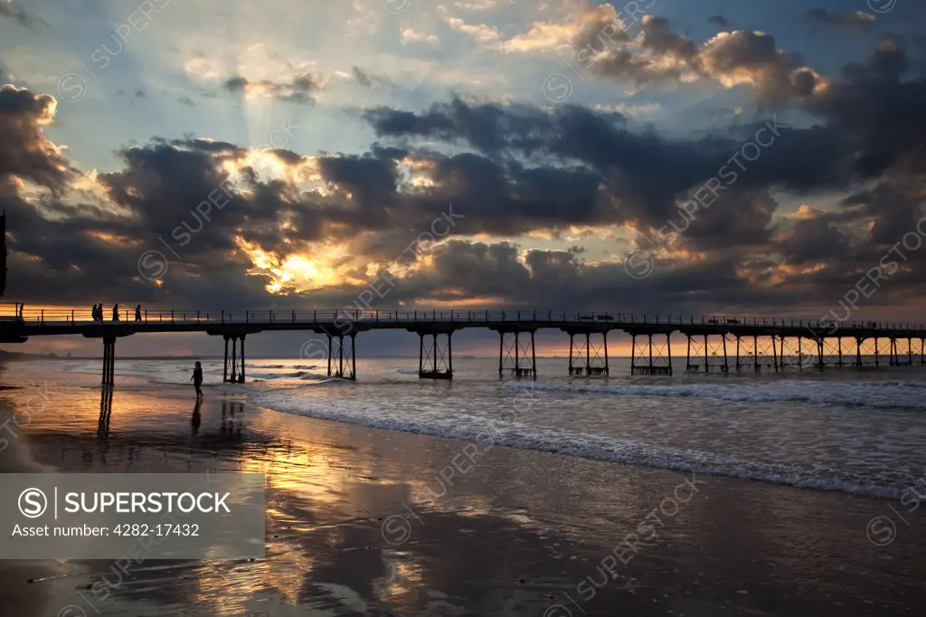 England, Redcar & Cleveland, Saltburn-By-The-Sea. Rays of sunlight from the setting sun over the Victorian pier at Saltburn-By-The-Sea.