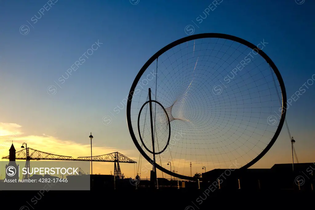 England, North Yorkshire, Middlesbrough. The Temenos sculpture by artist Anish Kapoor and structural designer Cecil Balmond on the banks of the River Tees. Middlesbrough's famous Transporter Bridge is in the background.