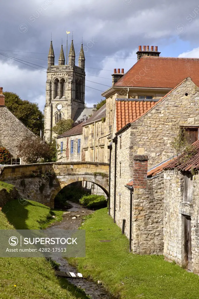 England, North Yorkshire, Helmsley. View along a stream in the market village of Helmsley towards All Saints Church.