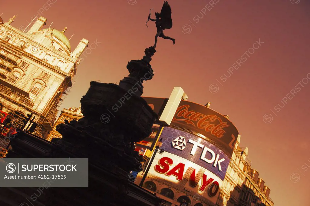 England, London, Piccadilly Circus. The statue of Eros on the Shaftesbury memorial fountain at Piccadilly Circus in London's West End silhouetted against advertising displays in the background.