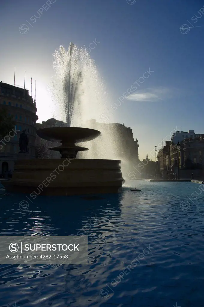 England, London, Trafalgar Square. A water fountain in Trafalgar Square backlit by sunlight.