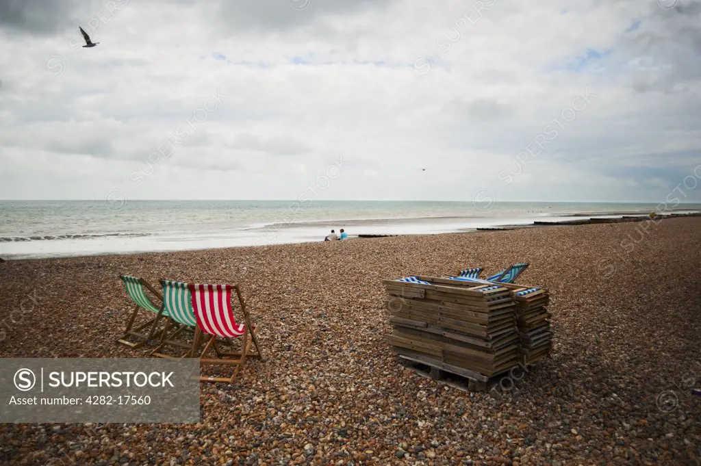 England, West Sussex, Worthing. Unused deckchairs on the pebble beach at Worthing.