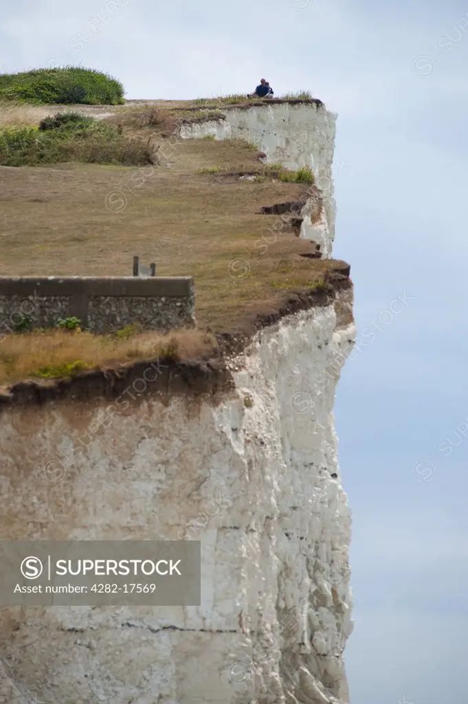 England, East Sussex, Birling Gap. A couple relaxing by the edge of the cliff top at Birling Gap near Beachy Head.