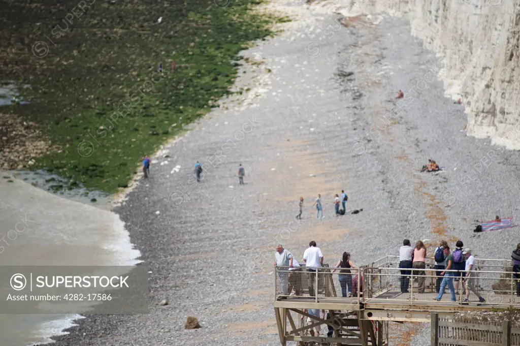 England, East Sussex, Birling Gap. People making their way down to the beach below the vertical white chalk sea cliffs near Beachy Head.
