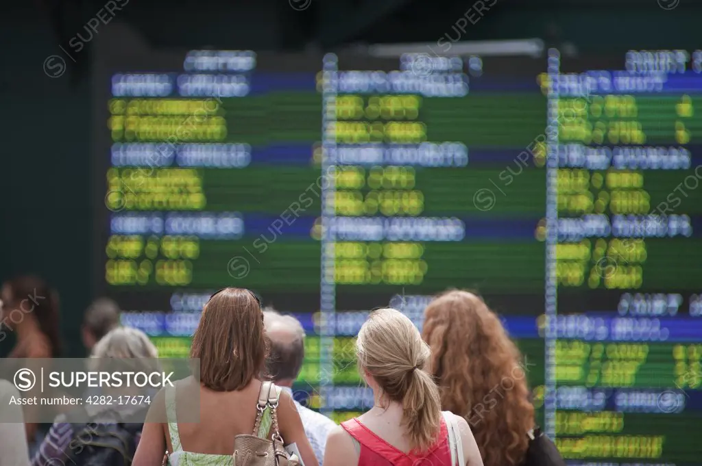 England, London, Wimbledon. Spectators looking up at an electronic score board at the Wimbledon lawn tennis championships in London.