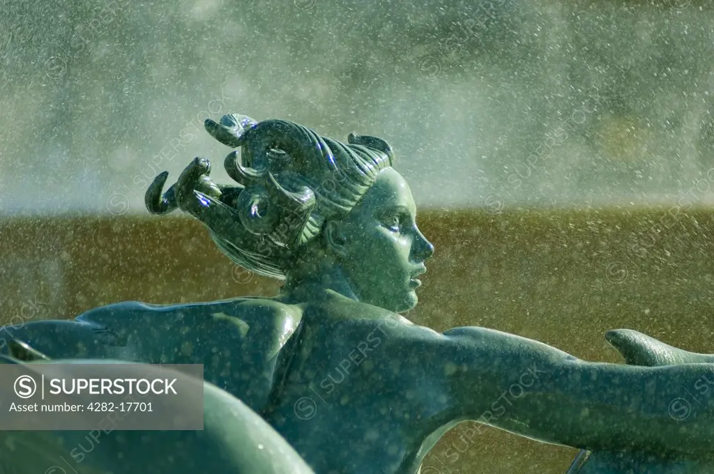 England, London, Trafalgar Square. Spray from a water fountain falling on a bronze sculpture of a mermaid in Trafalgar Square.