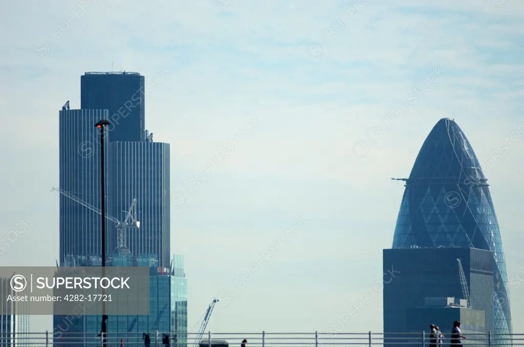 England, London, Blackfriars. Pedestrians crossing Blackfriars Bridge over the River Thames with tall office buildings of Tower 42 and 30 St Mary Axe in the City of London in the background.