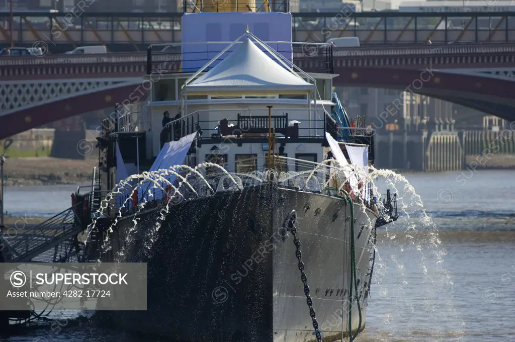 England, London, Victoria Embankment. Water being pumped from HMS President, an events venue permanently moored on Victoria Embankment in central London with Blackfriars Bridge in the background.