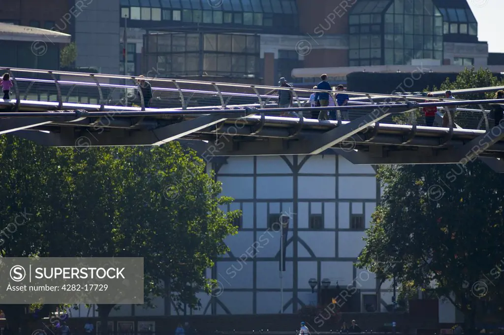 England, London, Millennium Bridge. Pedestrians crossing the Millennium footbridge over the River Thames in central London with Shakespeare's Globe Theatre in the background.