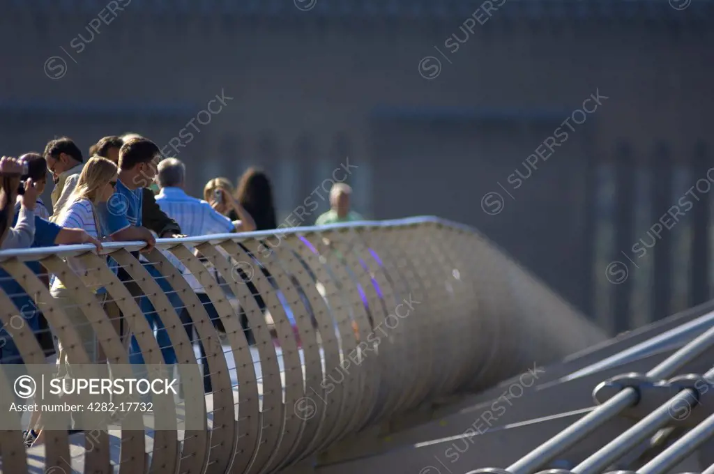 England, London, Millennium Bridge. Tourists sightseeing from the Millennium footbridge over the River Thames in central London.