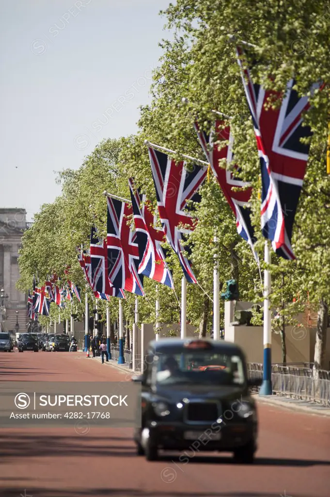 England, London, The Mall. A black London taxi travelling along the Mall from Buckingham Palace past Union Flags lining the route of the Royal Wedding.