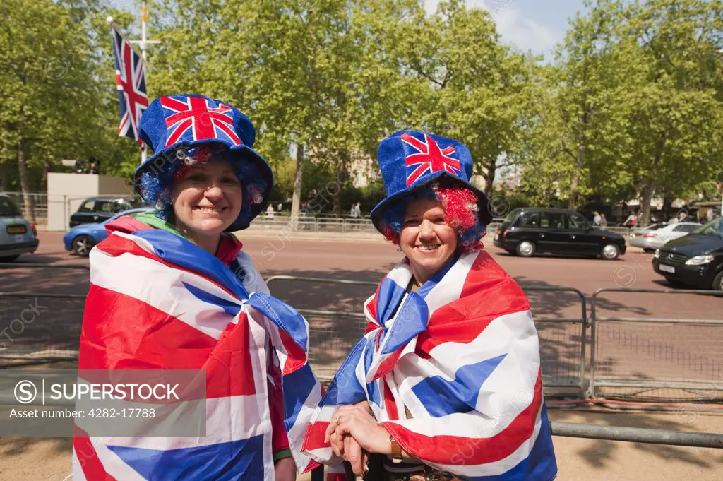 England, London, The Mall. Two happy Royal Wedding spectators on The Mall a day before the big event in central London, dressed in union flags.